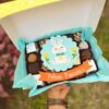 Delicioso Mix Box Conejito con una variedad de postres y una encantadora decoración temática de Pascua en fondant comestible.
