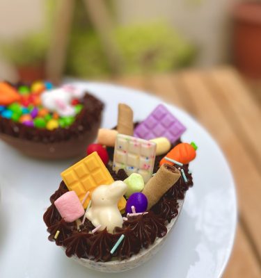 Exquisito huevo de Pascua con una mezcla irresistible de chocolate blanco y trocitos de galleta Oreo, decorado con una variedad de golosinas tentadoras.