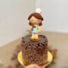 Encantadora mini torta de chocolate decorada con una figura de mamá cocinera y un topper dorado para celebrar el Día de la Madre.