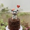 Una adorable mini torta artesanal adornada con una ratóncita, ideal para celebrar con un toque de dulzura.