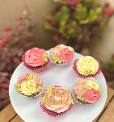 Seis cupcakes decorados con rosetones de buttercream y topper de Mamá con medio corazón.