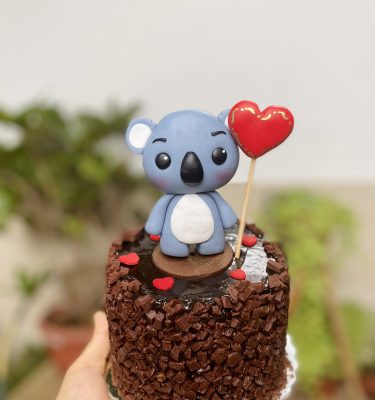 Mini torta de chocolate decorada con un koala enamorado y un corazón globo de fondant.