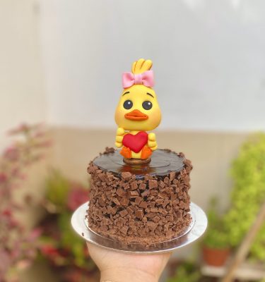 Encantadora mini torta de chocolate decorada con un adorable patito y un corazón dorado para celebrar el Día de la Madre.