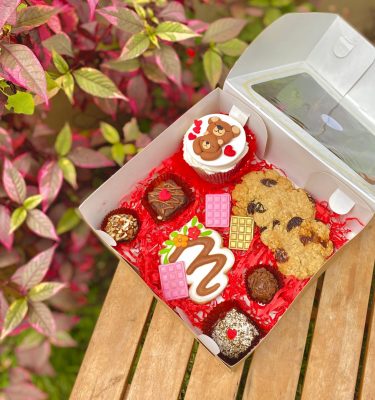 Encantador surtido de postres decorados para celebrar el Día de la Madre en una caja rústica.