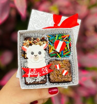 Cuatro mini postres decorados con fondant y toppings, presentados en una caja ecológica con opción de sticker personalizado.