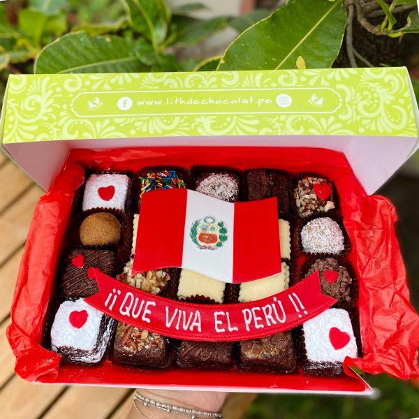 Veinte postres surtidos decorados con arte en oblea de la bandera del Perú, presentados en una caja de diseño marrón vintage con lazo de tela