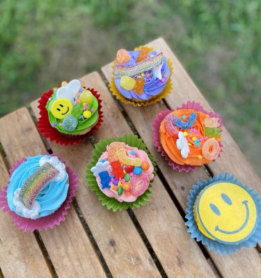 Pack de 6 cupcakes de arcoíris decorados con buttercream de colores y gomitas, empaquetados en una caja blanca con ventana.