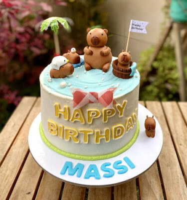 Torta decorada con buttercream celeste simulando agua y cuatro capibaras en la parte superior disfrutando de una pool party.
