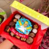 Mix Box con surtido de brownies, alfajores y trufas, decorados con fondant de Homero Simpson y cintillo con la frase "Feliz día papá".