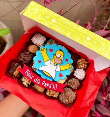 Mix Box con surtido de brownies, alfajores y trufas, decorados con fondant de Homero Simpson y cintillo con la frase "Feliz día papá".