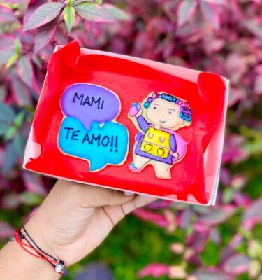 Pack de 2 galletas decoradas: una con burbujas de chat que dicen “Mami te amo” y otra con una ilustración de mamá con una chancla en la mano, por el Día de la Madre.