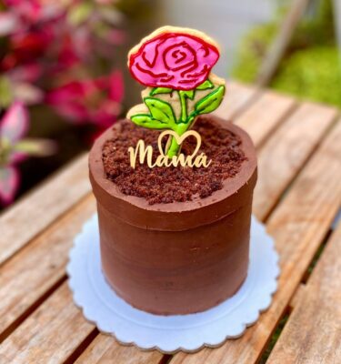 Mini torta en forma de maceta con una rosa de galleta en el centro y topper de cartulina que dice “Mamá”.