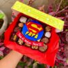 Caja Mix Box con variedad de brownies, trufas y alfajores decorados con fondant del logo de Superman y la palabra “Papá”, acompañados de un cintillo que dice “Para el mejor papá”.