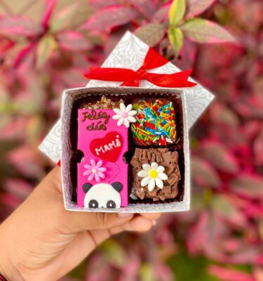 Cajita de 4 mini brownies con topper de fondant decorado con la carita de un medio panda, flores y la frase “Feliz día, mamá”.