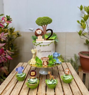 Torta de un piso decorada con cuatro animalitos modelados en fondant, un arbolito en fondant y hojas de cartulina que recrean un ambiente selvático.