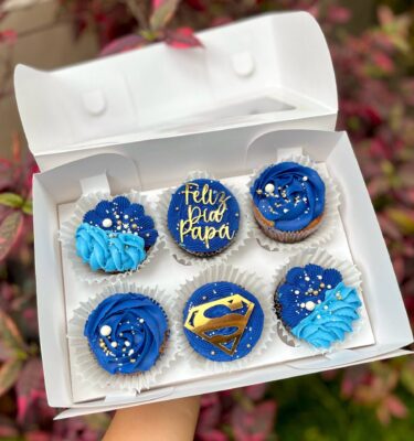 Pack de 6 cupcakes con buttercream, decorados con toppers de cartulina que incluyen la frase "Feliz día papá" y el logo de Superman, ideales para celebrar el Día del Padre.