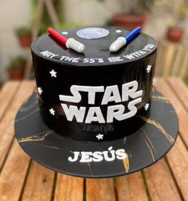 Torta de Star Wars decorada con fondant, logo de la saga y dos sables de luz en la parte superior.