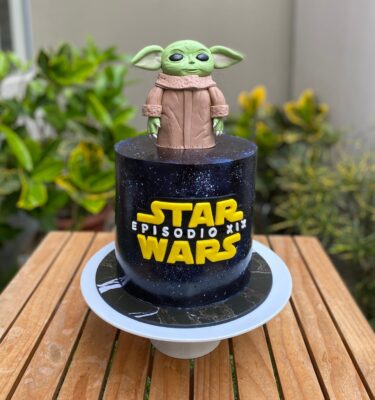 Torta de un piso con Grogu en la parte superior y el logo de Star Wars en el frente, decorada con fondant.