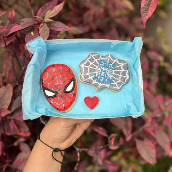 Dúo de galletas decoradas: una con la figura de Spider-Man y otra con la frase “Eres mi héroe”.