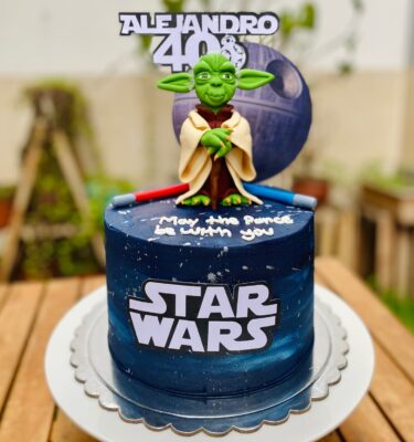 Torta de Star Wars de un piso decorada con fondant, logo de Star Wars, Maestro Yoda en fondant, dos sables de luz y toppers de cartulina.
