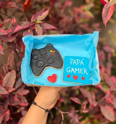 Dúo de galletas decoradas con temática gamer: una en forma de mando de PlayStation y otra con la frase “Papá Gamer”.