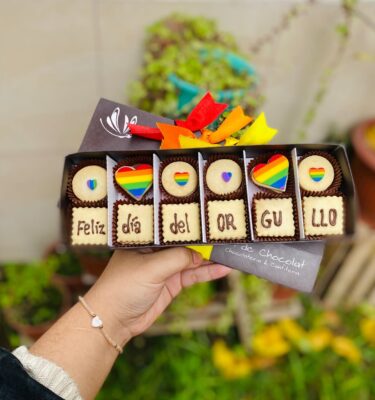Caja vintage de 12 alfajores decorados con corazones en los colores de la bandera Pride y la frase “Feliz Día del Orgullo”.