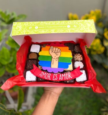 Mix Box Orgullo con brownies, trufas y alfajores decorados con fondant de bandera Pride y la frase “Amor es amor”.