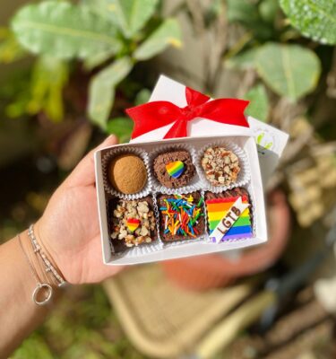 Caja con 3 brownies y 3 trufas decoradas con fondant: dos corazones con los colores de la bandera Pride y un cuadrado arcoíris con la palabra “LGTB”