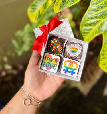 Mini Four de brownies decorados con fondant: uno con la frase “Love is Love”, otro con un corazón en colores Pride y otro con símbolos de mujer entrelazados con los colores del arcoíris.