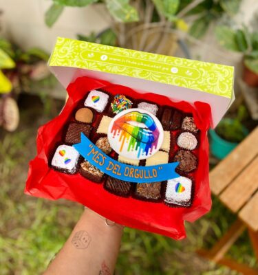 Mix Box con brownies, trufas y alfajores decorados con topper de fondant que muestra una boca mordiendo el labio con los colores de la bandera Pride y un banner que dice "Mes del Orgullo".