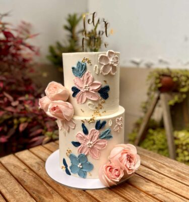 Torta decorada con flores de buttercream y flores naturales en tonos armoniosos.