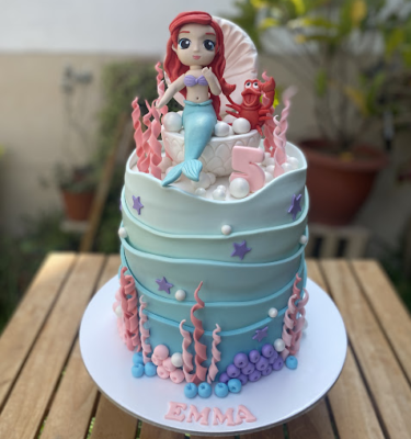 Torta de un piso forrada en fondant con temática de La Sirenita. Incluye figuras en fondant de Ariel y Sebastián, decorada con corales y elementos marinos.