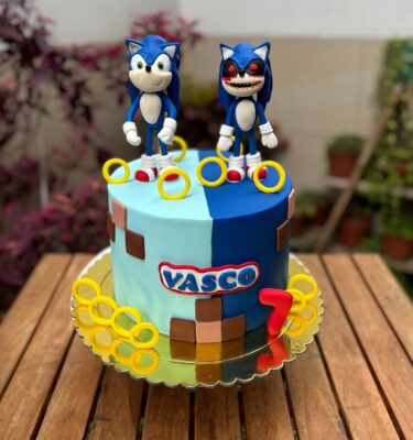 Torta de Sonic partida en dos mitades: un lado celeste con Sonic bueno en fondant, y el otro lado azul con Sonic versión malvada, también en fondant. Forrada completamente en fondant con diseño simétrico y vibrante.