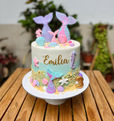 Torta de un piso decorada con buttercream en tonos marinos, colas de sirena en fondant y detalles de estrellas de mar, conchitas y corales.