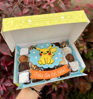Caja Mix Box con trufas, brownies y alfajores decorados con un Pikachu de fondant y un banner que dice "Feliz Día del Niño"