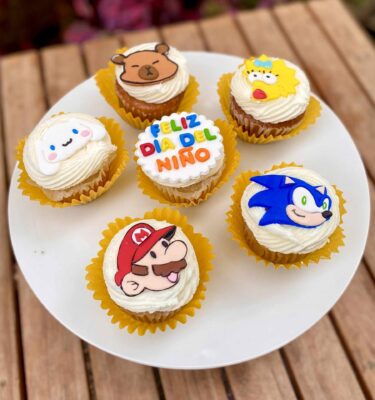 Caja de 6 cupcakes decorados en fondant con personajes: capibara, Sonic, Mario, Maggie Simpson, Cinnamoroll y uno con la frase “Feliz Día del Niño”