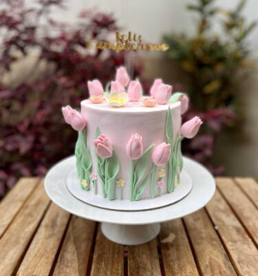 Torta de un piso cubierta en fondant blanco, decorada con elegantes flores 3D de azúcar en tonos delicados