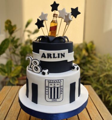 Torta de dos pisos en blanco y negro con temática de Alianza Lima. Lleva el escudo del club en el primer piso, estrellas decorativas en la parte superior y una pequeña botella de ron como detalle final.
