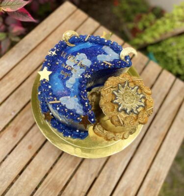 Torta de media luna y sol, bañada en buttercream, con perlas comestibles, estrellas doradas y topper personalizado.