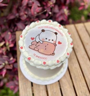 Burncake bañado en buttercream blanco, decorado con delicados rosetones, pequeños corazones de fondant y una imagen central tierna de los ositos Dudu y Bubu