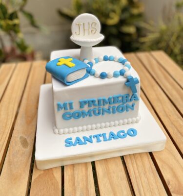 Torta de Primera Comunión de un piso, forrada en fondant blanco y decorada con cáliz, libro y rosario en fondant, más la frase “Mi Primera Comunión”.