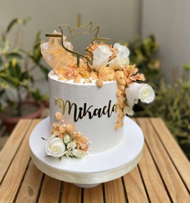 Torta de Primera Comunión de un piso, bañada en buttercream con rosetones, flores naturales, caramelo decorativo moderno y topper de silueta del Espíritu Santo.
