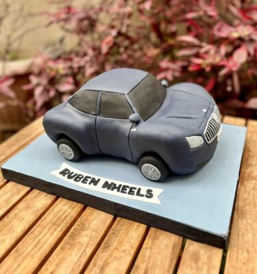 Torta tallada en forma de auto, acabada en fondant y pre bañada en ganache de chocolate, con personalización de nombre.