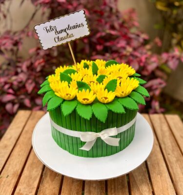 Torta de fondant en forma de ramo de girasoles, decorada en verde y con girasoles de fondant en la parte superior.