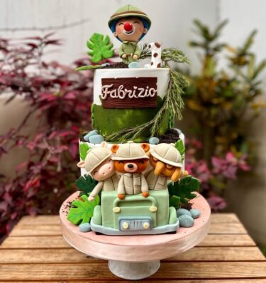 Torta de dos pisos temática plim plim safari, bañada en buttercream y decorada con figuras en fondant de animalitos y elementos de safari.