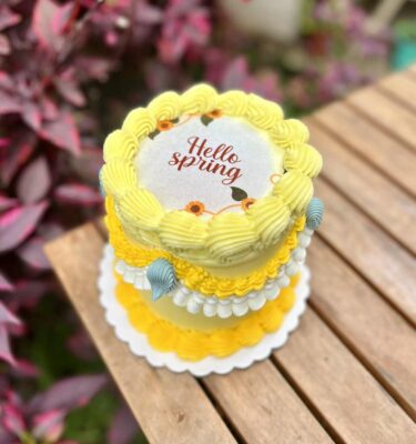 Un burncake decorado en tonos amarillos, con detalles florales que celebran la llegada de la primavera. Al encenderlo, revela un mensaje oculto lleno de color y alegría.