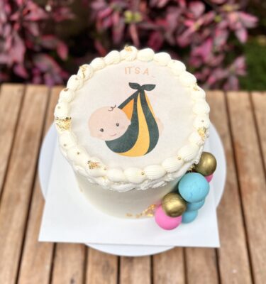 Burncake revelación con buttercream, decorado con bolas de chocolate y papelitos dorados