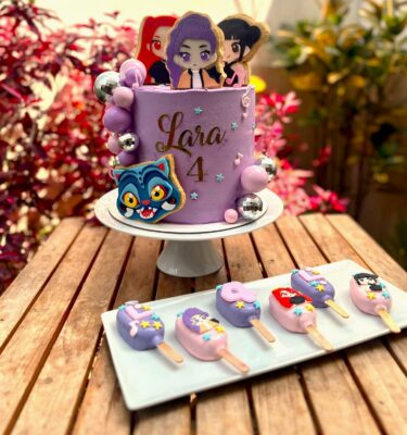 Torta temática de las Huntrix decorada con bolas no comestibles y personajes de Huntrix elaborados en galletas.