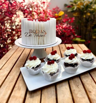 Torta para bodas de papel cubierta con oblea, decorada con frambuesas frescas y seis velas ondeadas.