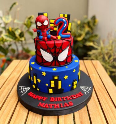 Torta de dos pisos de Spiderman decorada en fondant, con figura 3D de Spiderman en la parte superior.